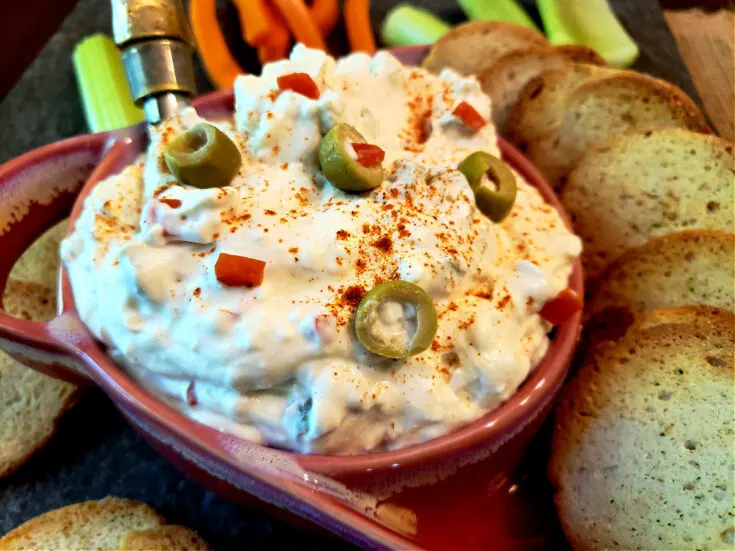 Classic cream cheese and green olives spread appetizer served with crackers and crudités