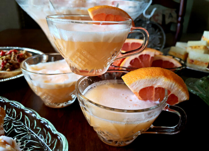 Sherbet Punch Recipe in a crystal punch bowl with punch glasses garnished with orange slices