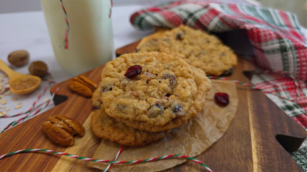 wooden board with oatmeal cranberry pecan cookies with a holiday theme setting