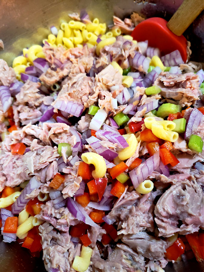 Adding tuna fish to the pasta salad ingredients