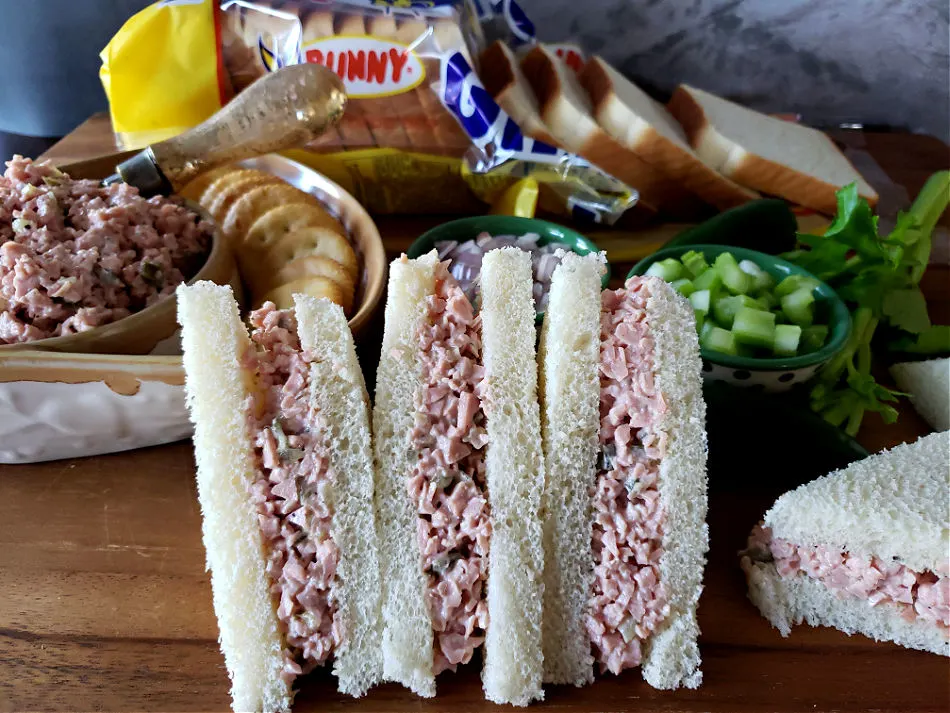 Bologna salad sandwiches on a wooden cutting board