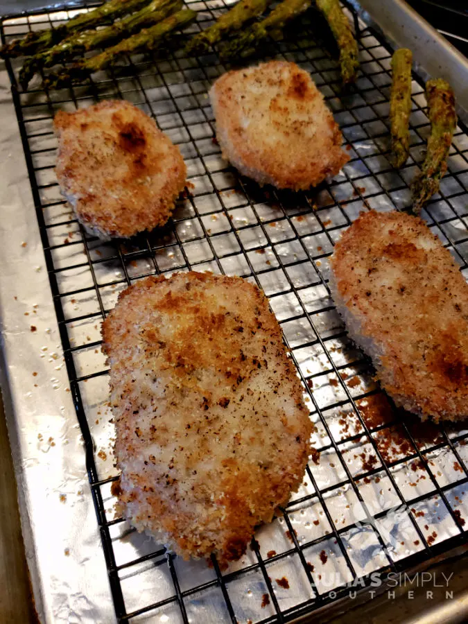 easy baked pork chops with crispy coating on a baking rack with asparagus