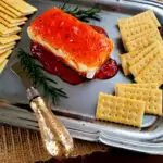 Best pepper jelly cream cheese appetizer on a silver serving platter with crackers garnished with rosemary sprigs