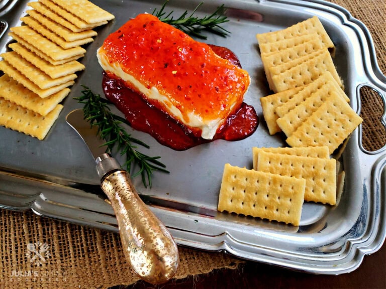 Best pepper jelly cream cheese appetizer on a silver serving platter with crackers garnished with rosemary sprigs