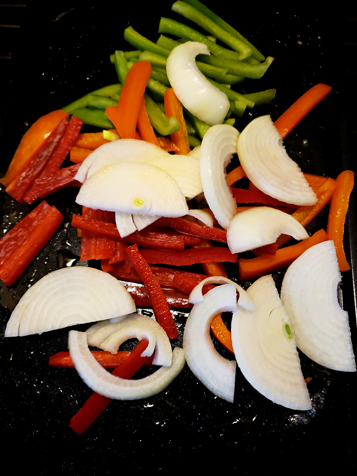 Sliced Bell Peppers and Onions sautéing on a griddle