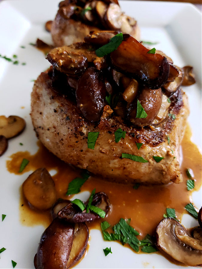 Tender thick pork chops pan seared and topped with sautéed mushrooms