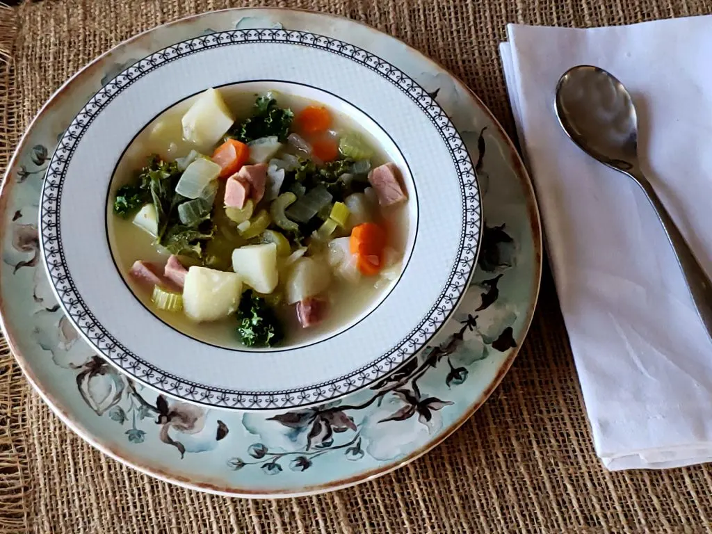 Blue bowl with cotton pattern with ham potato kale soup serving