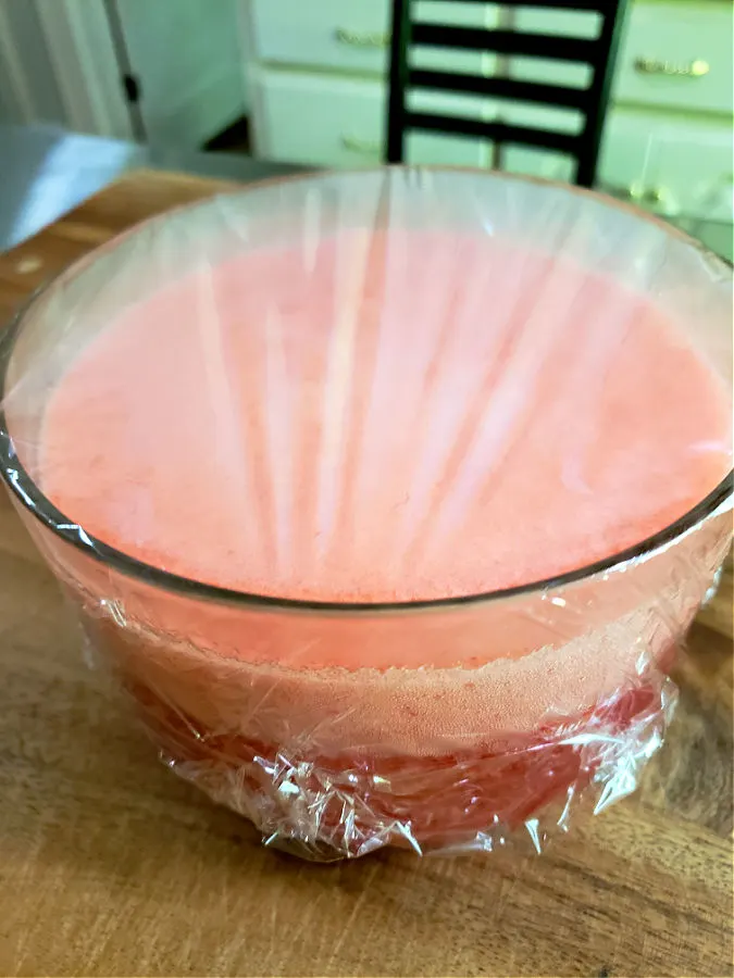 bowl with applesauce salad mixture covered with plastic wrap before refrigerating to set