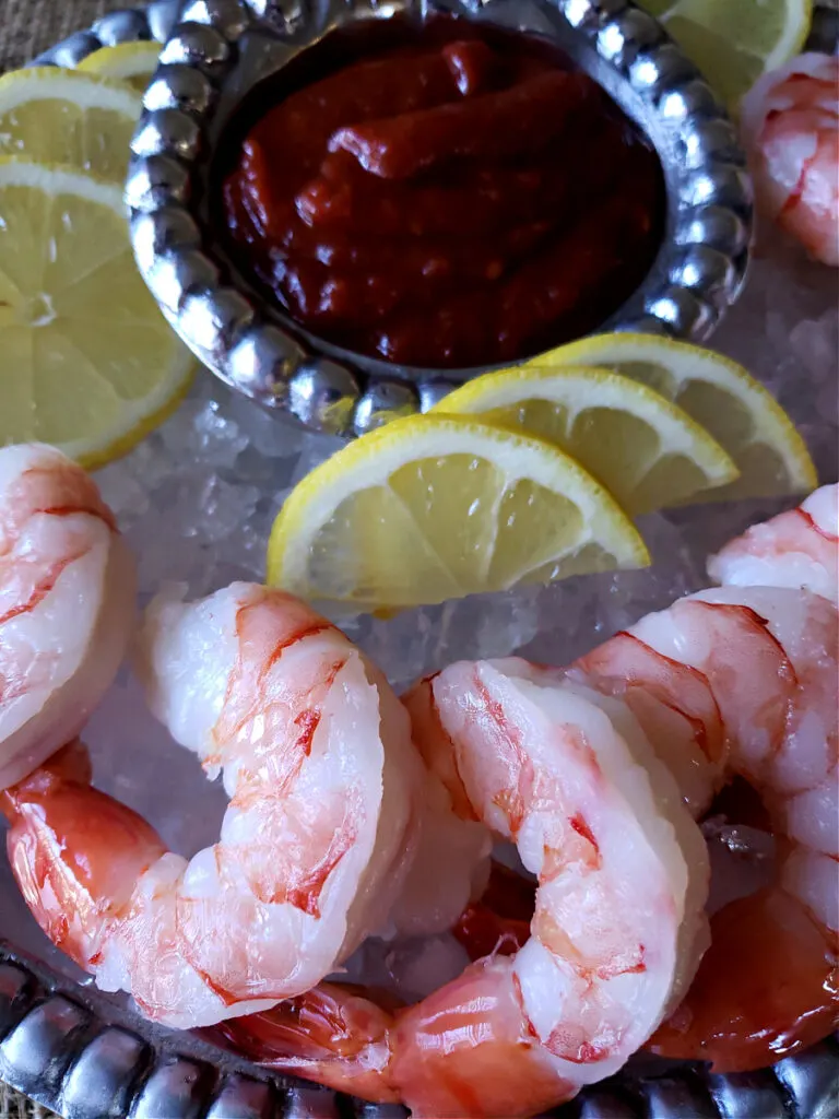 Vintage silver tray with shrimp on a bed of ice with red sauce and lemons