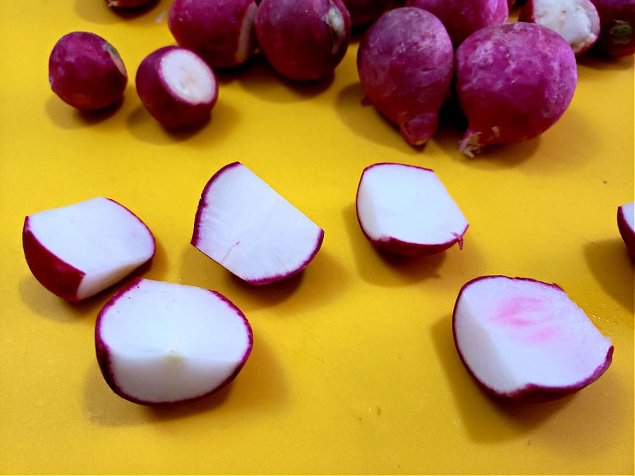 cutting board with raw radishes being prepped