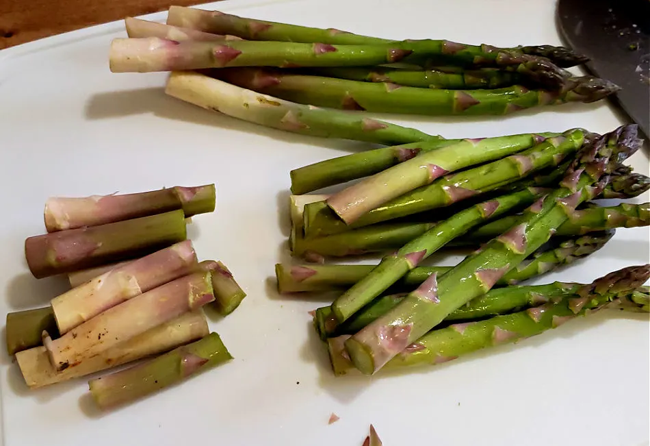 Prepping fresh asparagus spears on a cutting board