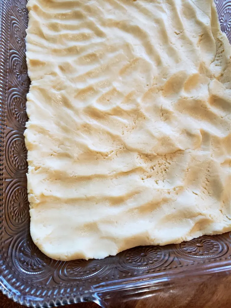 Pressing cake mix and cream cheese cookie bar dough into baking dish - Granny's goody bars recipe