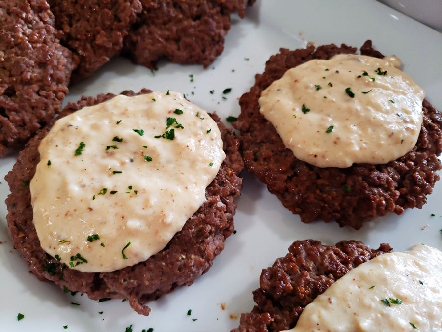 Hamburger Steaks with creamy country pepper gravy on a serving platter garnished with chopped parsley