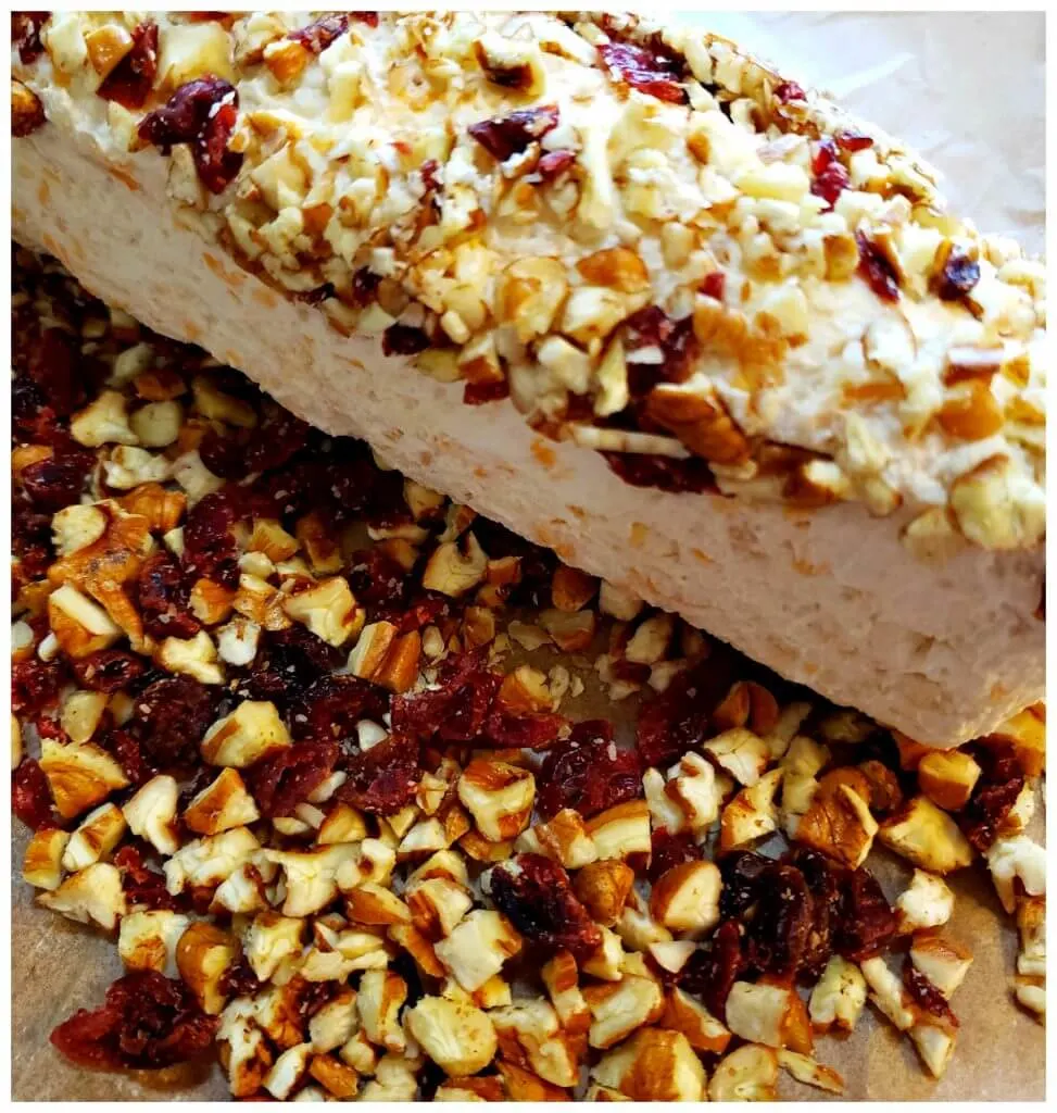 Rolling a cheese ball to coat in dried cranberries and pecans