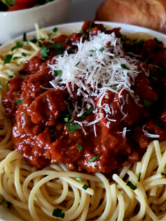 Spaghetti Sauce Recipe on a bed of fresh cooked pasta topped with grated Parmesan cheese and garnished with fresh parsley