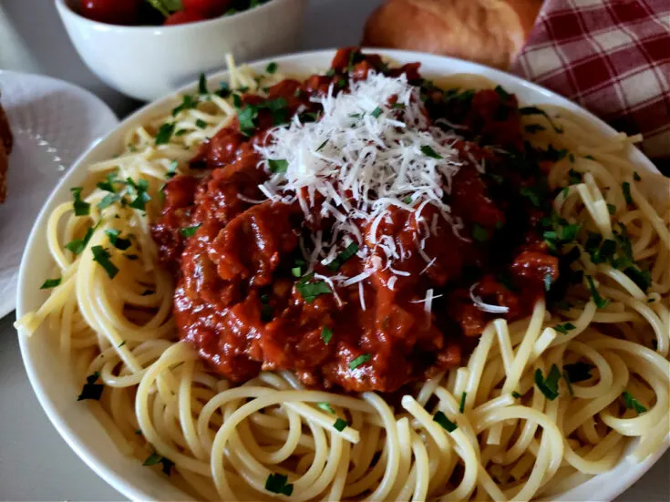 Spaghetti Sauce Recipe on a bed of fresh cooked pasta topped with grated Parmesan cheese and garnished with fresh parsley