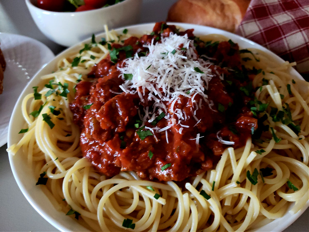 Spaghetti Sauce Recipe on a bed of fresh cooked pasta topped with grated Parmesan cheese and garnished with fresh parsley