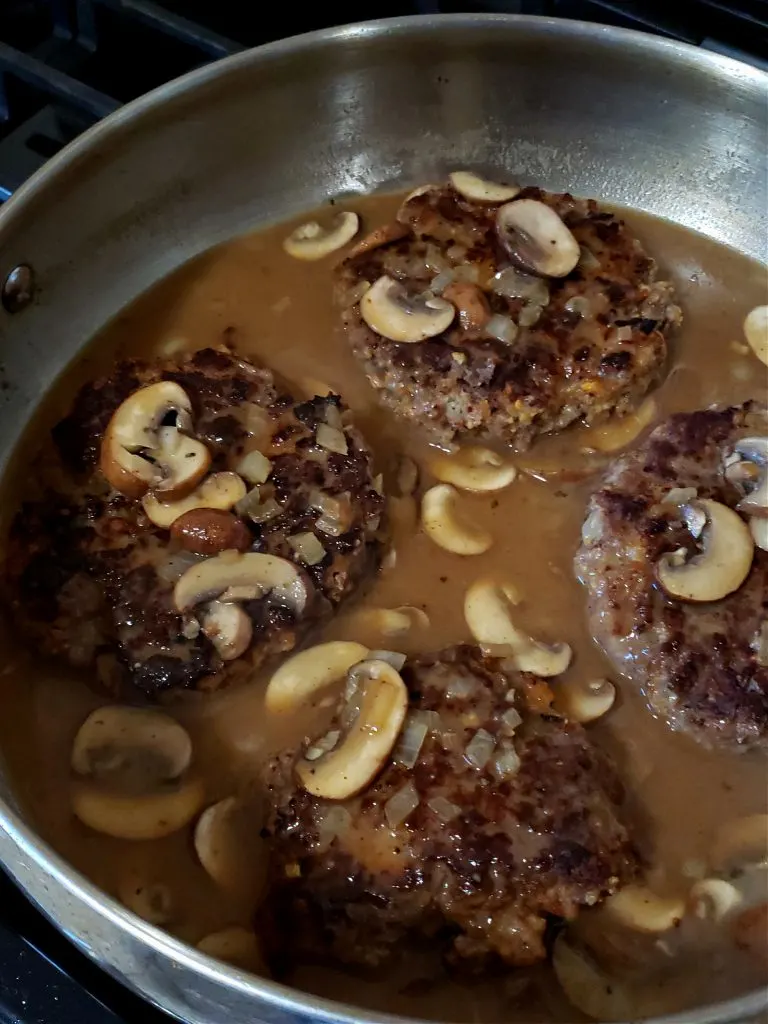Salisbury Steaks in mushroom gravy simmering in a skillet