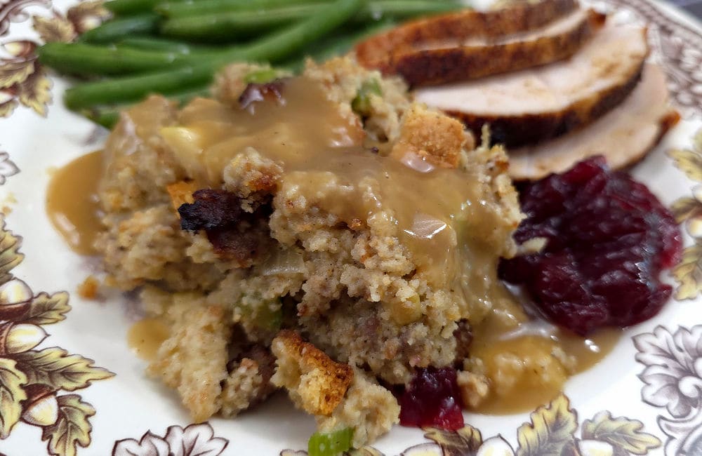 Southern cornbread dressing with gravy on a plate with sauteed string beans and sliced turkey