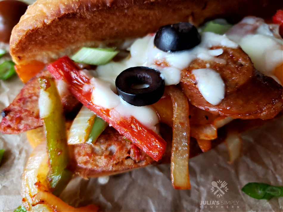 Italian Sausage and peppers recipe on sandwiches with cheese and black olives on toasted sub rolls