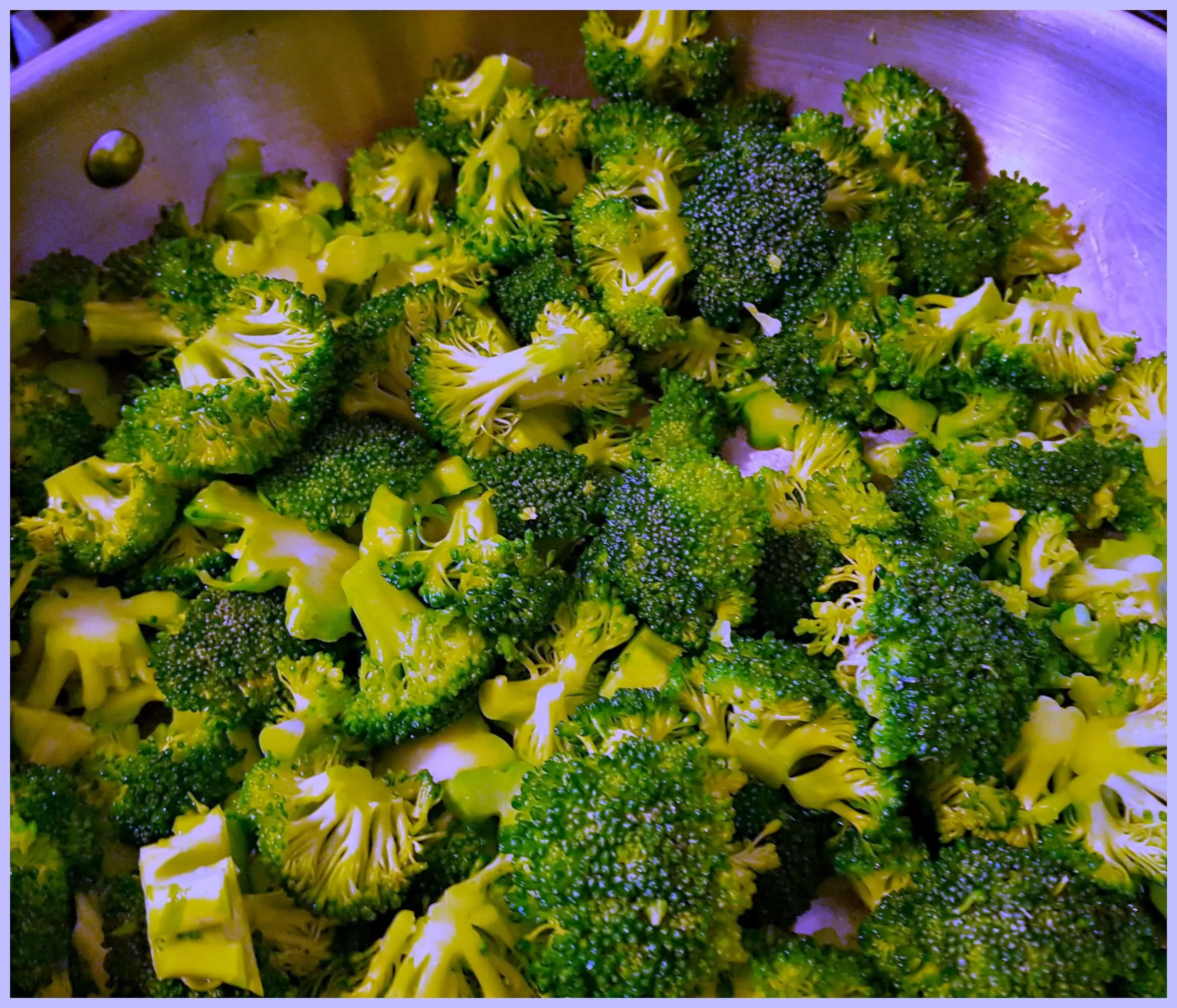 fresh broccoli cooking in a stainless skillet