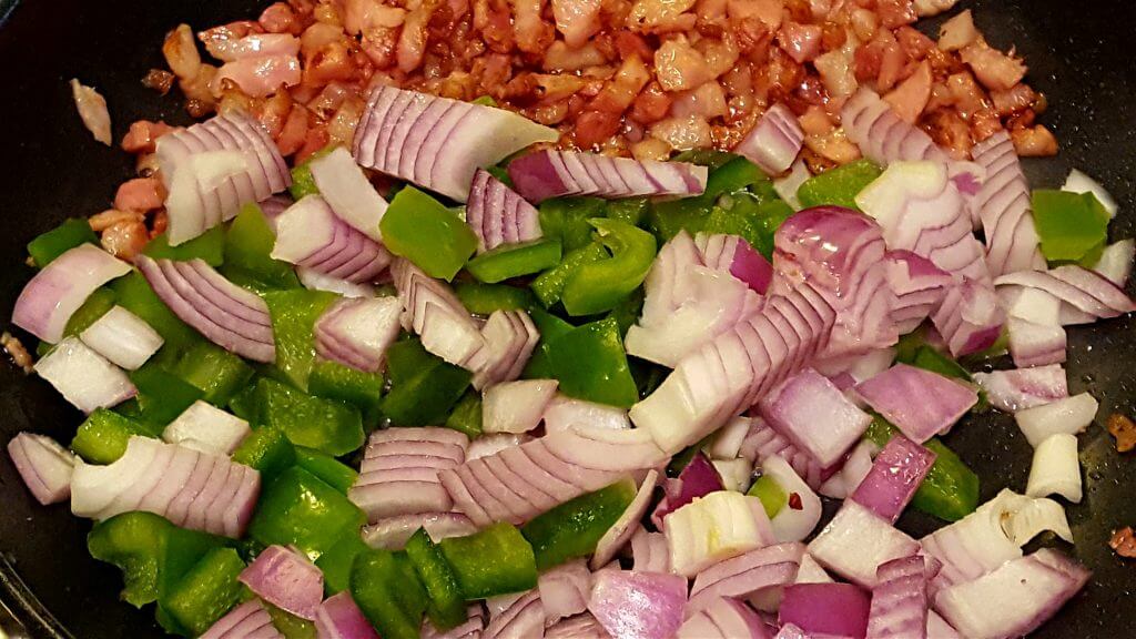 Diced green pepper, red onion, and pancetta in a skillet for an Italian Pasta Salad