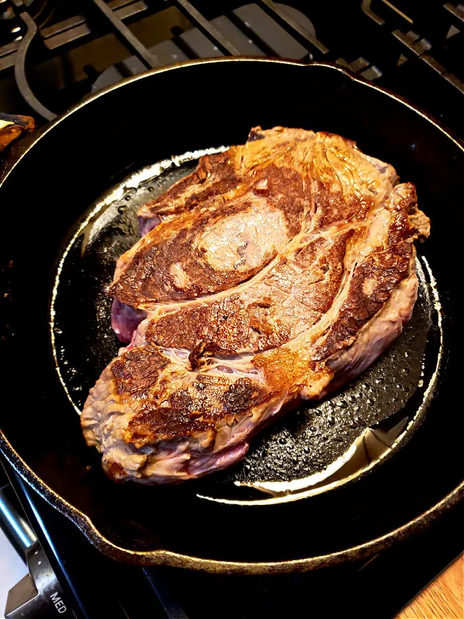 cast iron skillet searing a chuck roast before slow cooking