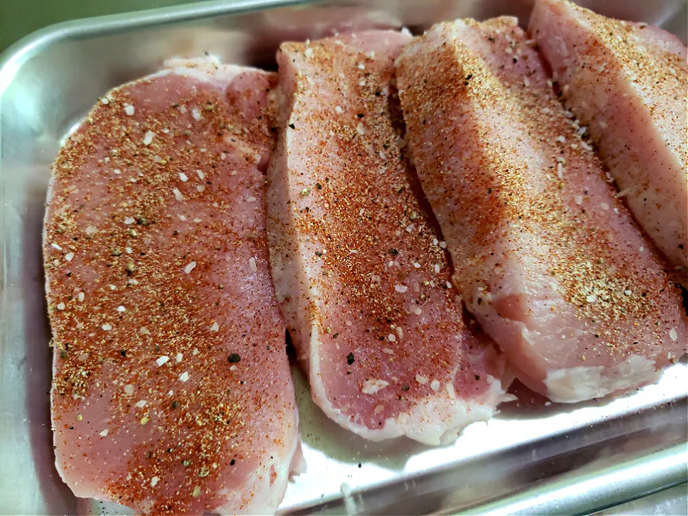 a small sheet pan with seasoned un-cooked pork chops