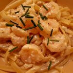 shrimp with garlic cream sauce over pasta and garnished with chives