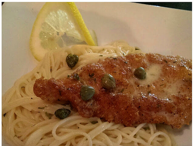 chicken and pasta with lemon butter sauce garnished with capers and a lemon slice