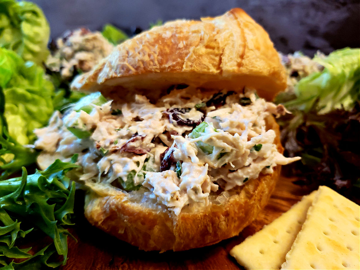 Creamy Southern style chicken salad on a flaky croissant with lettuce in the background