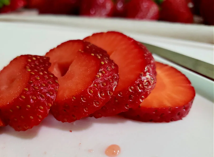 Slicing fresh strawberries on a cutting board