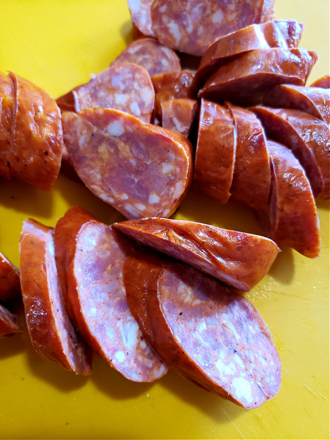 a yellow cutting mat with slices of Cajun Andouille sausage