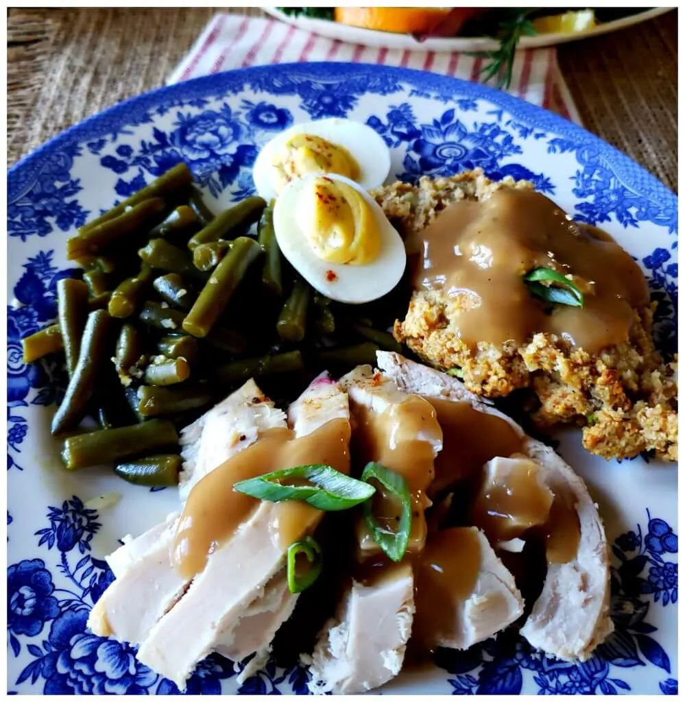Plate with sliced turkey, stuffing, green beans, deviled eggs and gravy