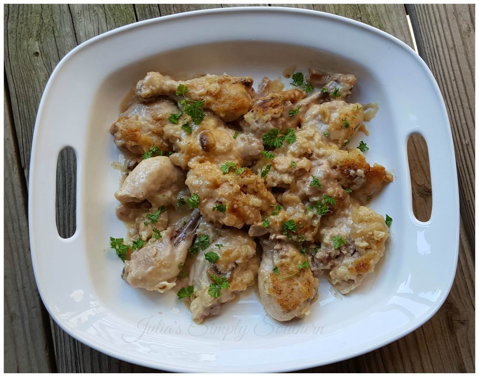 smothered chicken in a white serving platter garnished with parsley