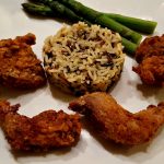 fried quail on a plate with wild rice and asparagus