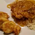 Smothered Pork Chops on a white plate with rice and fried yellow squash