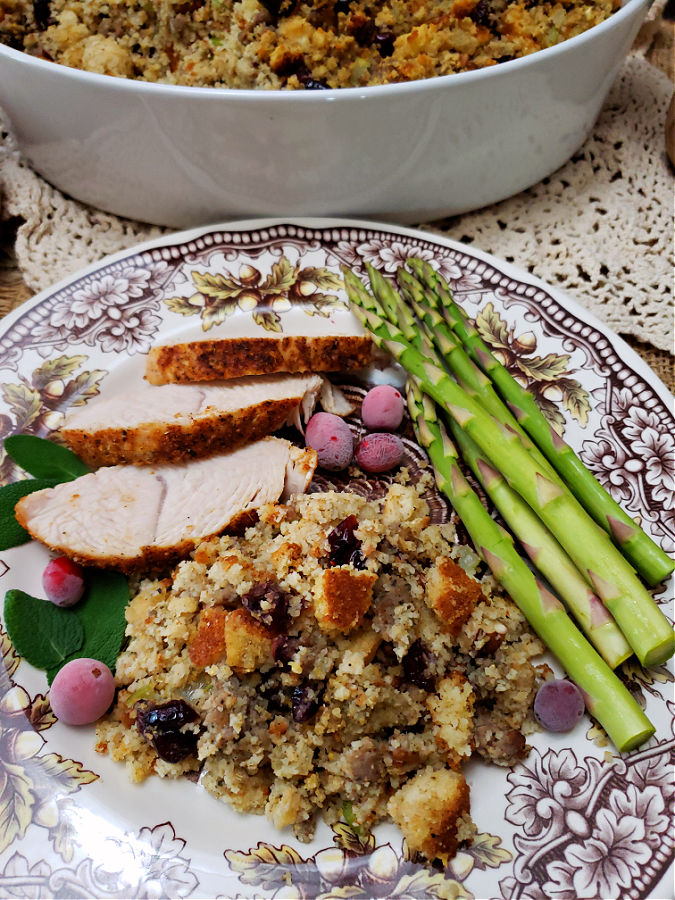 brown and white plate with serving of cornbread dressing with sausage, cranberries, and pecans