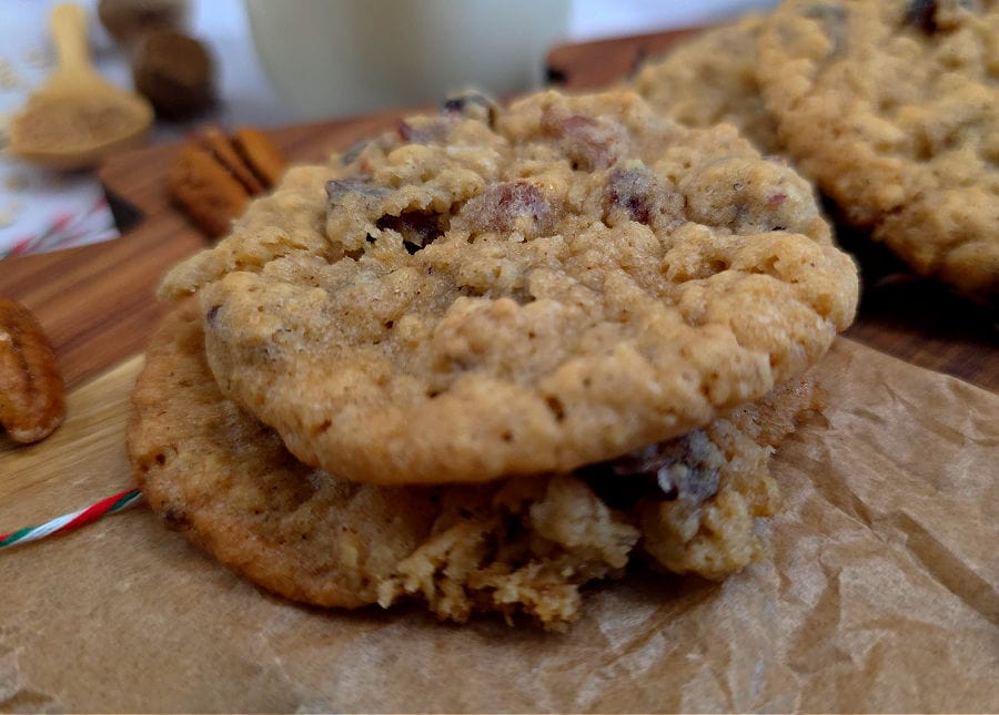 Southern grandma Christmas cookies with oatmeal, cranberries, and pecans on parchment with a glass of milk