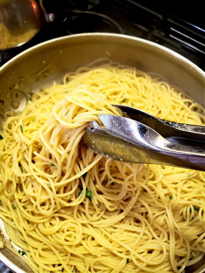 Tossing spaghetti pasta in the infused olive oil sauce