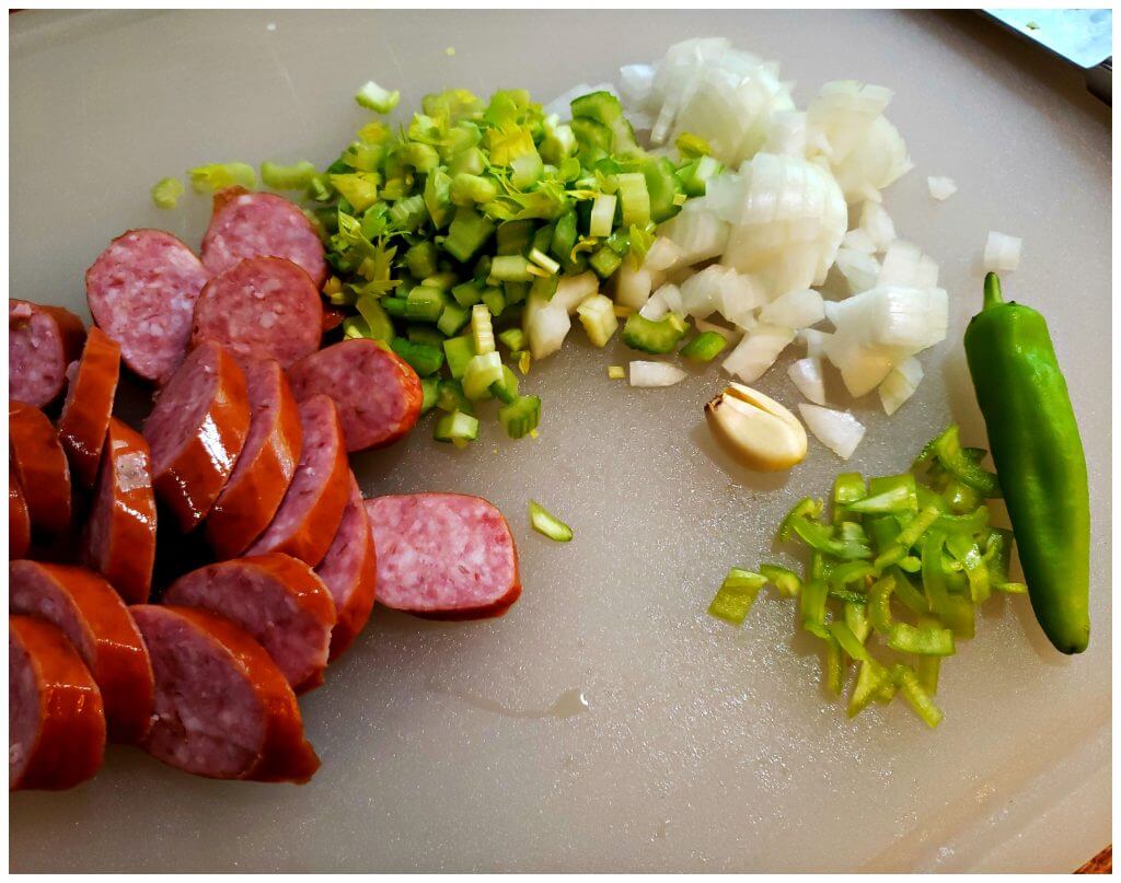 Cutting board with slices sausage and diced vegetables for bean soup