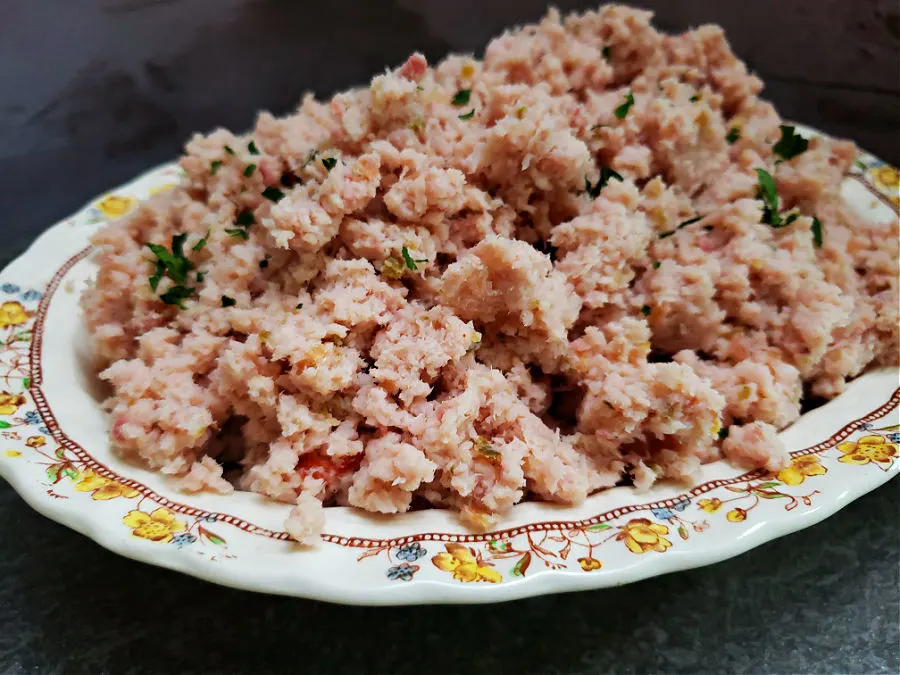 A vintage bowl with yellow floral containing ham salad spread without mayonnaise.