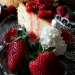 Strawberry topping recipe for cheesecake on a glass plate surrounded by fresh strawberries and whipped cream