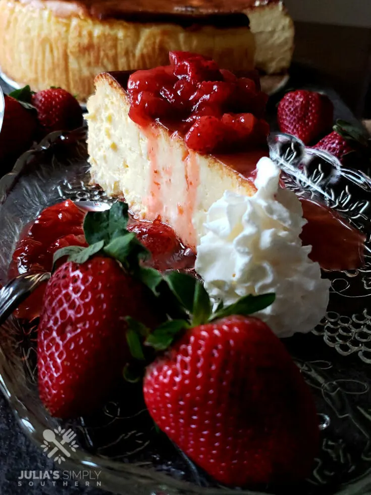 Strawberry topping recipe for cheesecake on a glass plate surrounded by fresh strawberries and whipped cream