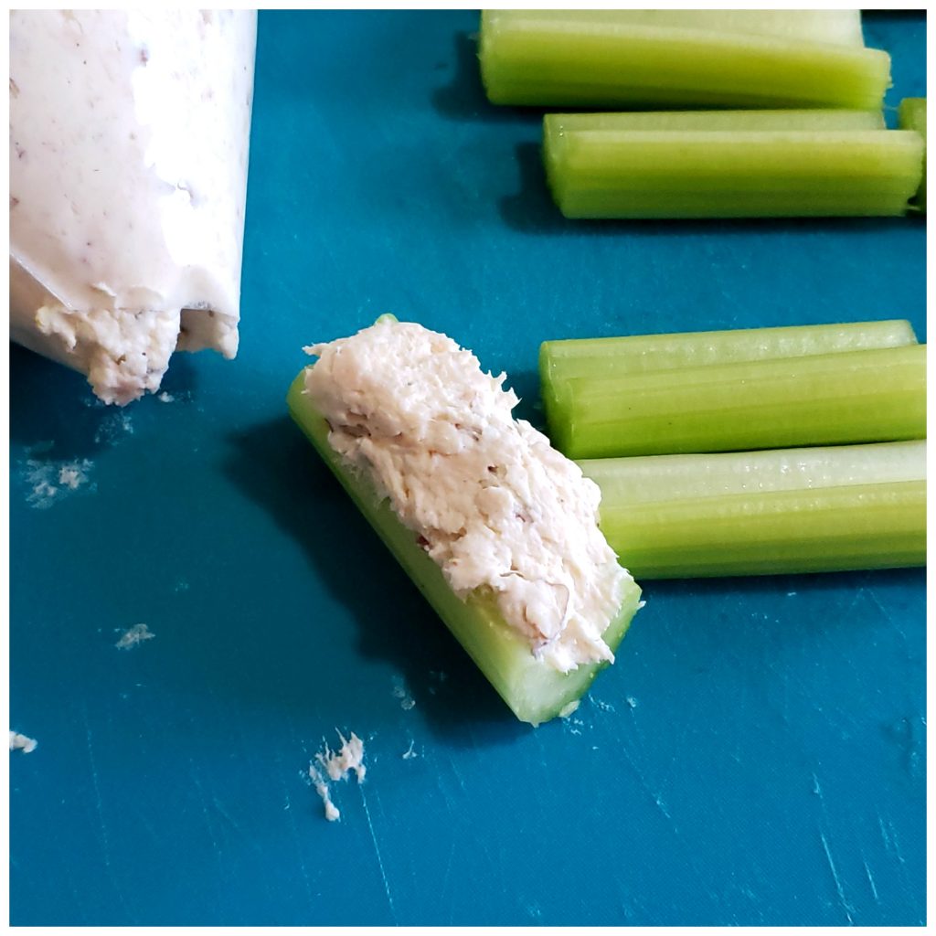 Piping a chicken cream cheese filling into celery bites