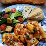 casserole dish with stuffed shells and a blue and white plate with stuffed shells with ricotta cheese filling with a simple salad and piece of Italian bread.