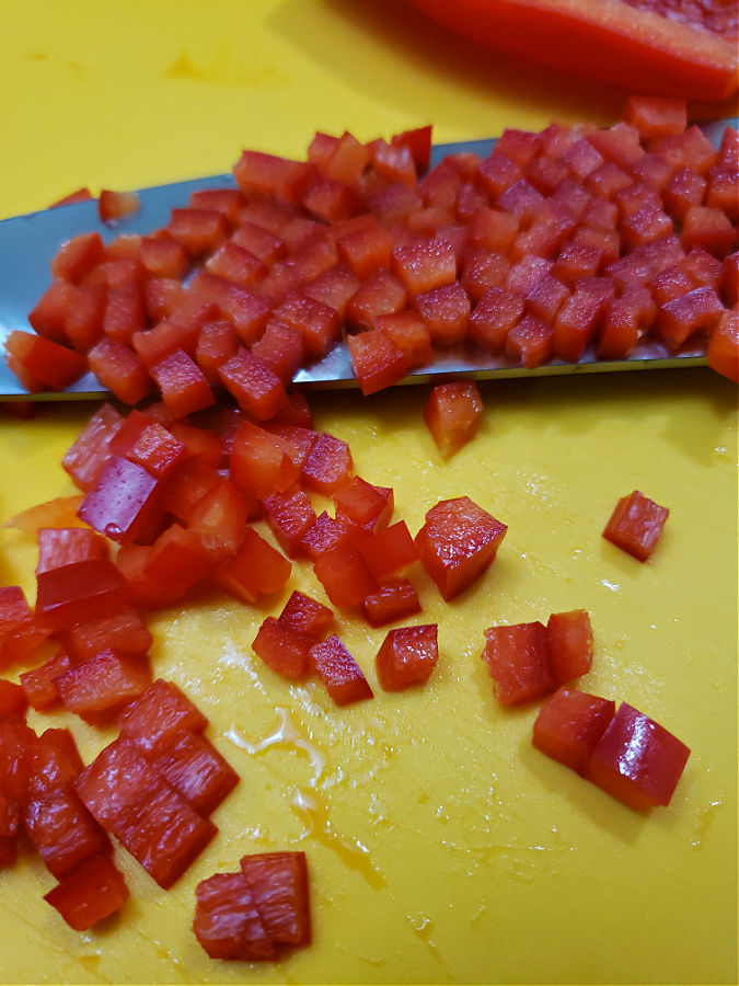 diced red bell pepper on a yellow cutting mat