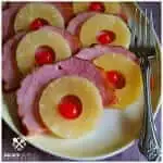 Crock Pot Holiday Ham - Pineapple Glazed slow cooker ham topped with pineapple rings and cherries on a yellow platter with a serving fork