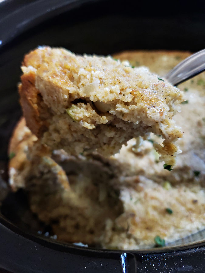 spooning a serving of cornbread dressing from the Crock Pot