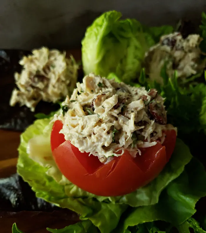 Chicken salad stuffed tomato on a bed of crisp lettuce